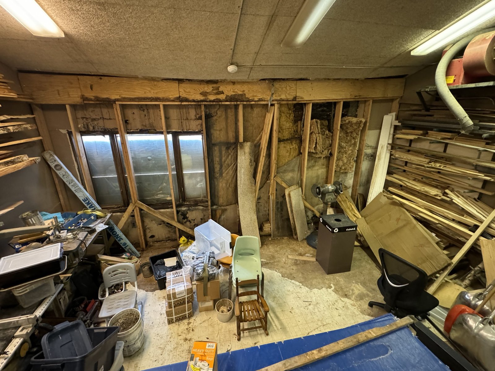 A room full of scraps of wood. The wall is partially destroyed, showing insulation and wooden studs.