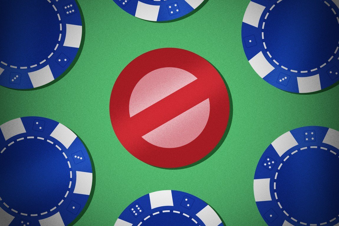 Blue gambling chips surround a red chip in the shape of a “no” symbol, with a slash through the center of the chip.