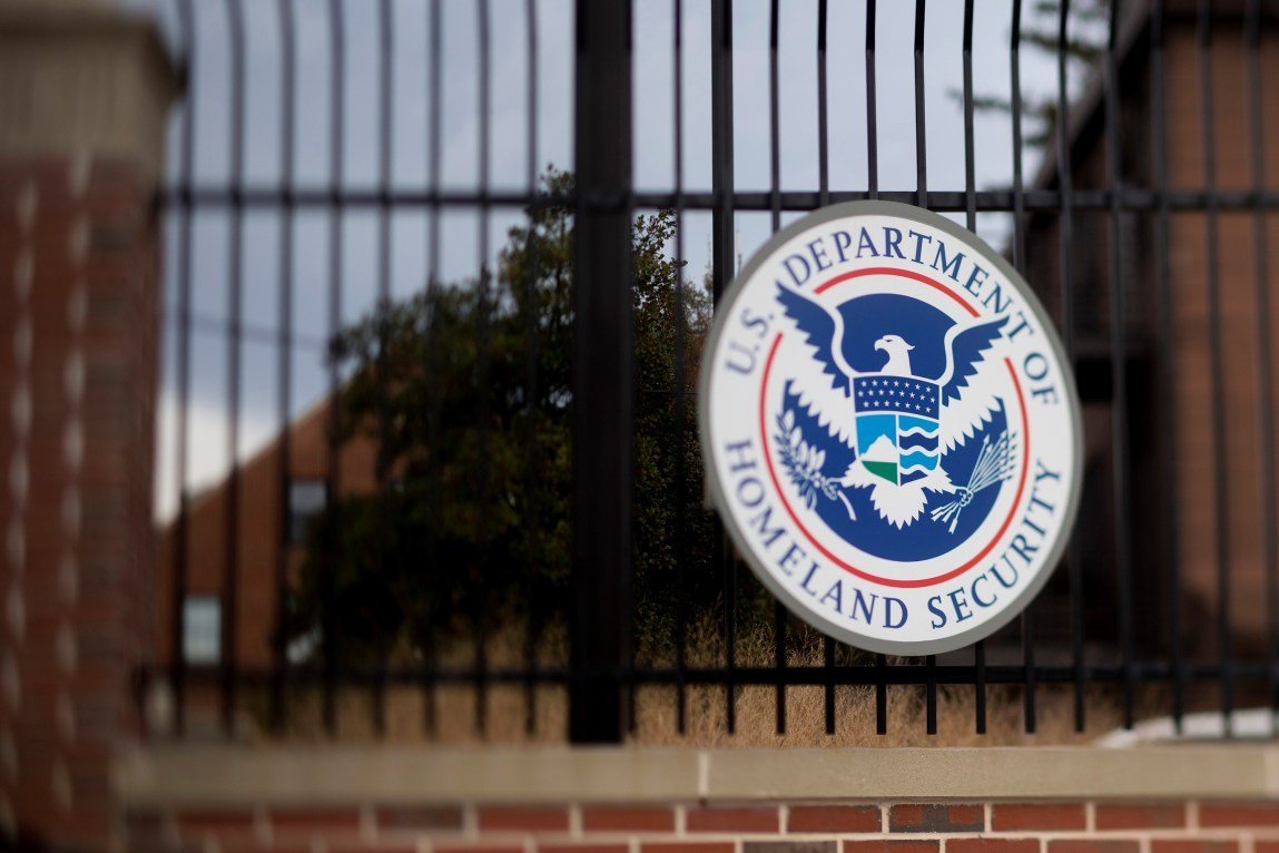 The Department of Homeland Security logo attached to a fence. The edges of the image are blurred.